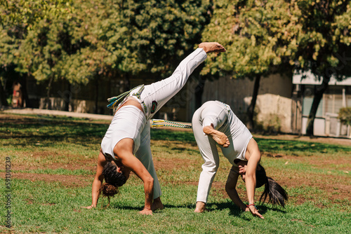 mujeres practicando patadas, ejercicios y capoeira en la ciudad con su ropa de capoeira en un parque verde en un día soleado.