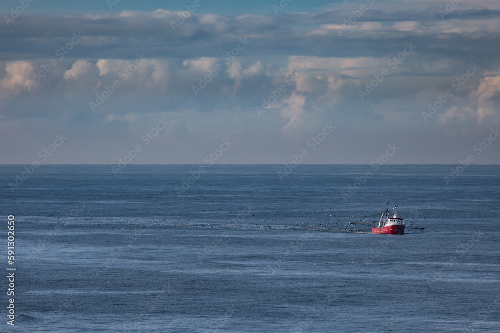 A cutter with lifted drag nets on the North sea close to the beach