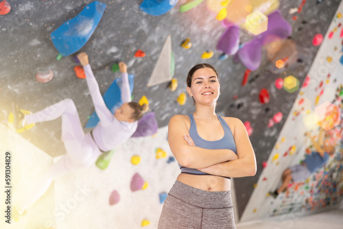 Young sporty woman posing against background of wall at climbing wall