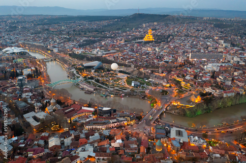 Picturesque general view from drone of Georgian city of Tbilisi on banks of Mtkvari River at spring dusk