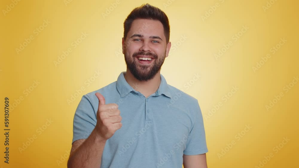 Like. Caucasian young man in t-shirt raises thumbs up agrees with something, gives positive reply recommends advertisement likes good. Handsome bearded guy isolated alone on yellow studio background Like. Caucasian young man in t-shirt raises thumbs up agrees with something, gives positive reply recommends advertisement likes good. Handsome bearded guy isolated alone on yellow studio background