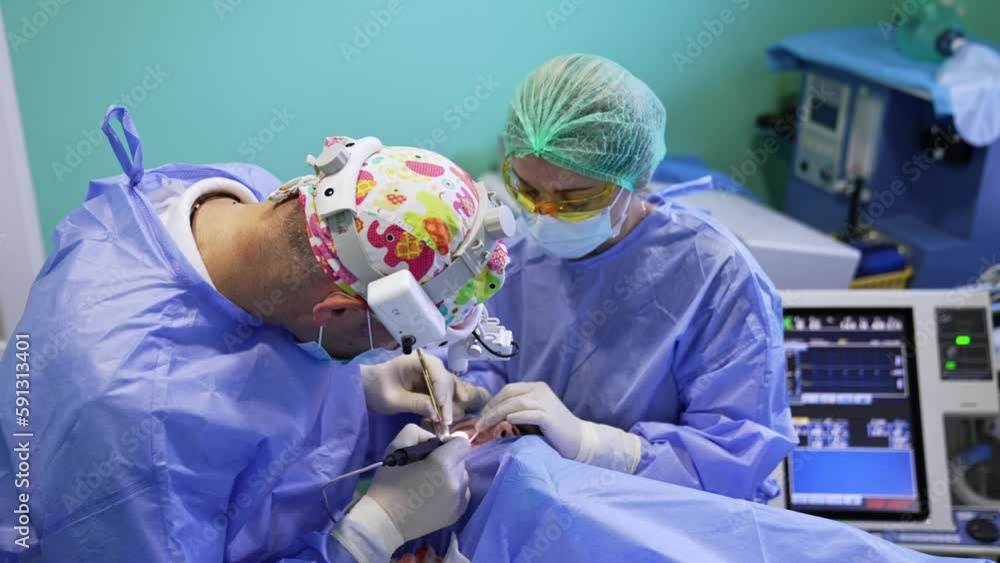 Surgeon carefully uses tools at the eye of a patient. Eyelid surgery procedure. Female doctor assisting. Top view. Surgeon carefully uses tools at the eye of a patient. Eyelid surgery procedure. Female doctor assisting. Top view.
