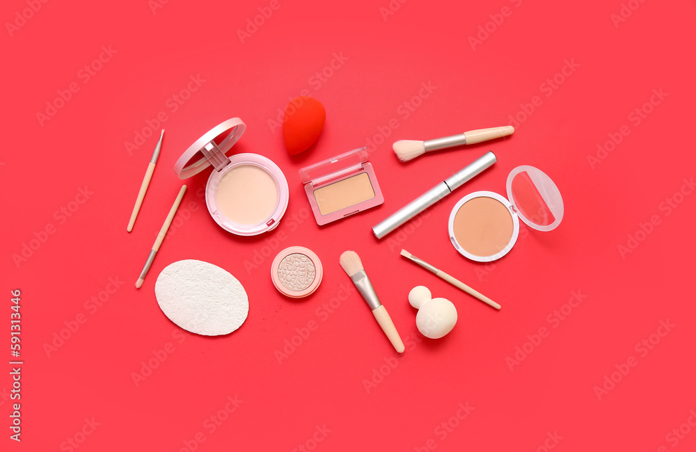 Decorative cosmetics with makeup brushes and sponges on red background Decorative cosmetics with makeup brushes and sponges on red background