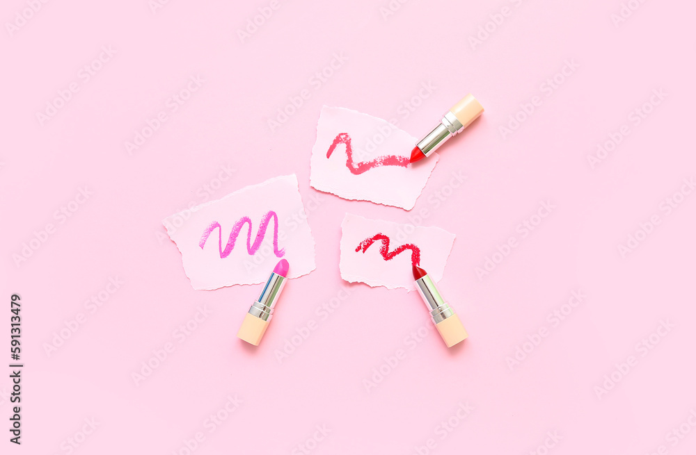 Lipsticks and papers with strokes on pink background Lipsticks and papers with strokes on pink background