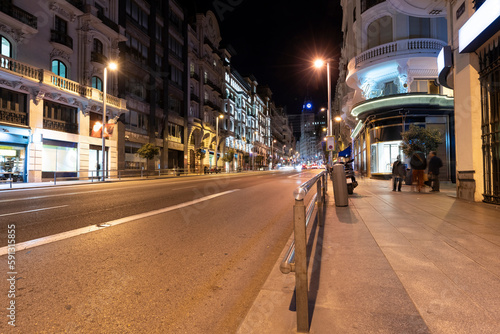 Historic old buildings in the shopping street Gran Via in Madrid illuminated at night with light trails from traffic