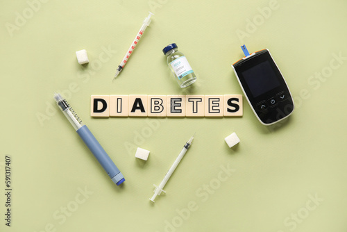 Word DIABETES with glucometer, insulin, lancet pen and sugar on green background. Diabetes concept