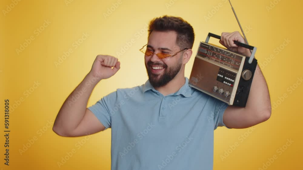 Happy Caucasian man using retro tape record player to listen music, disco dancing of favorite track, having fun, entertaining, fan of vintage technologies. Handsome guy isolated on yellow background Happy Caucasian man using retro tape record player to listen music, disco dancing of favorite track, having fun, entertaining, fan of vintage technologies. Handsome guy isolated on yellow background
