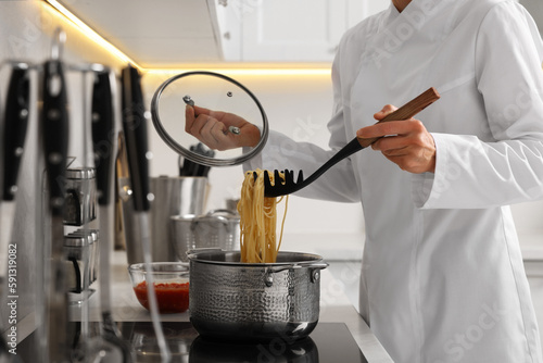 Professional chef cooking delicious pasta in saucepan indoors, closeup