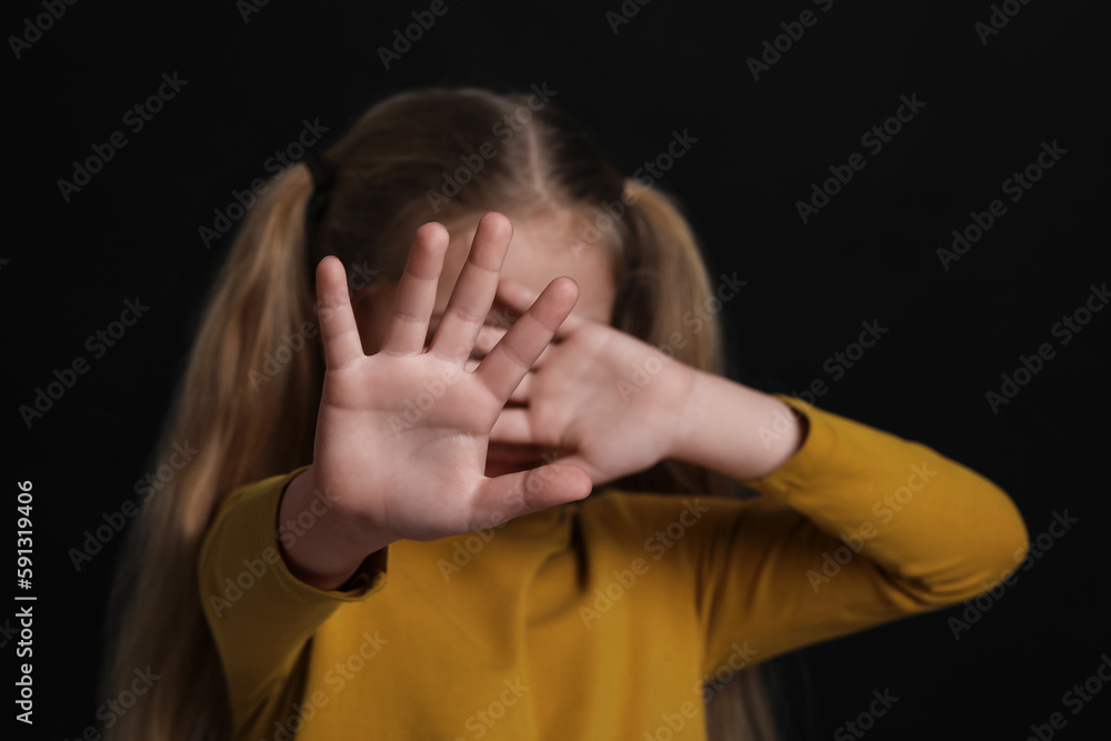 Girl making stop gesture against black background, focus on hands. Children's bullying Girl making stop gesture against black background, focus on hands. Children's bullying