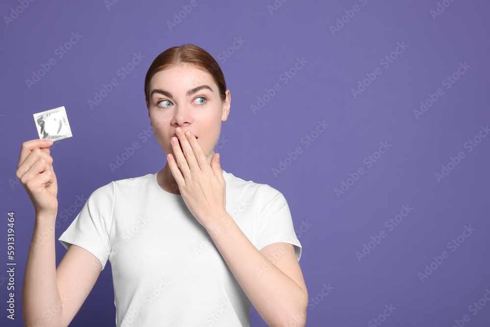Woman holding condom on purple background, space for text. Safe sex Woman holding condom on purple background, space for text. Safe sex