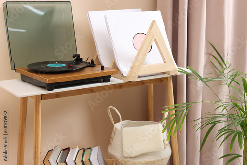 Stylish turntable with vinyl record on console table in cozy room © New Africa