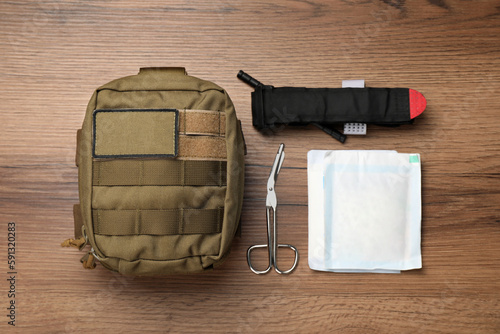 Military first aid kit on wooden table, flat lay