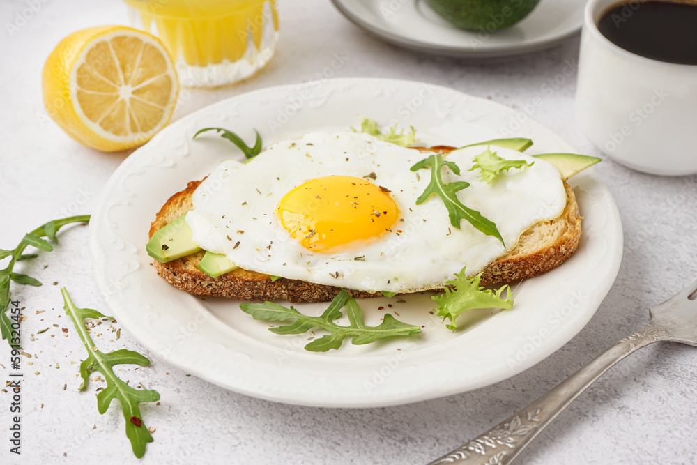 Delicious sandwich with fried egg, arugula and avocado on light background Delicious sandwich with fried egg, arugula and avocado on light background