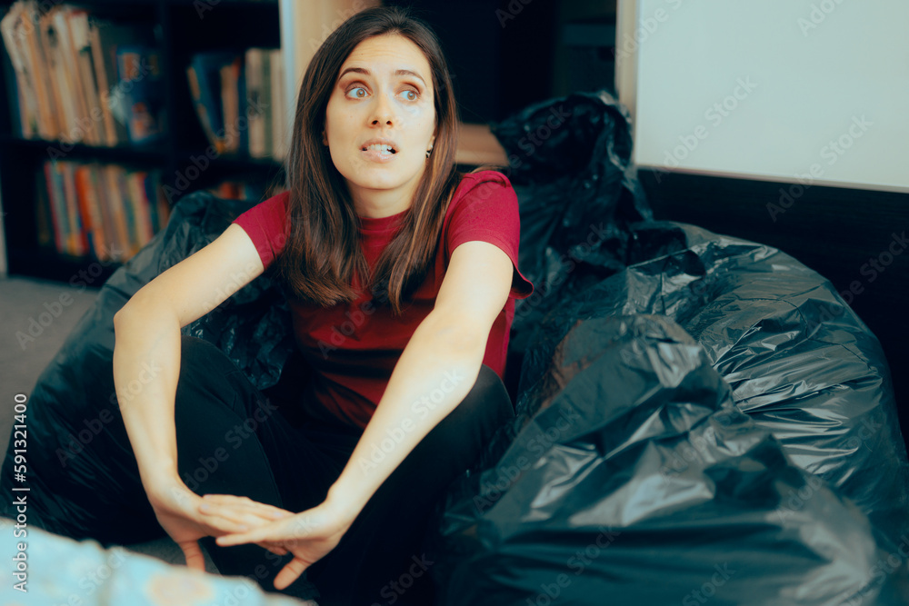 Woman Surrounded with Plastic Bags after De-cluttering and Editing her Wardrobe. Fashionista feeling guilty for irresponsible over consumption of fast fashion


