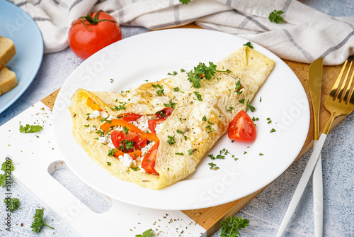 Tasty omelet with tomatoes and parsley on light table