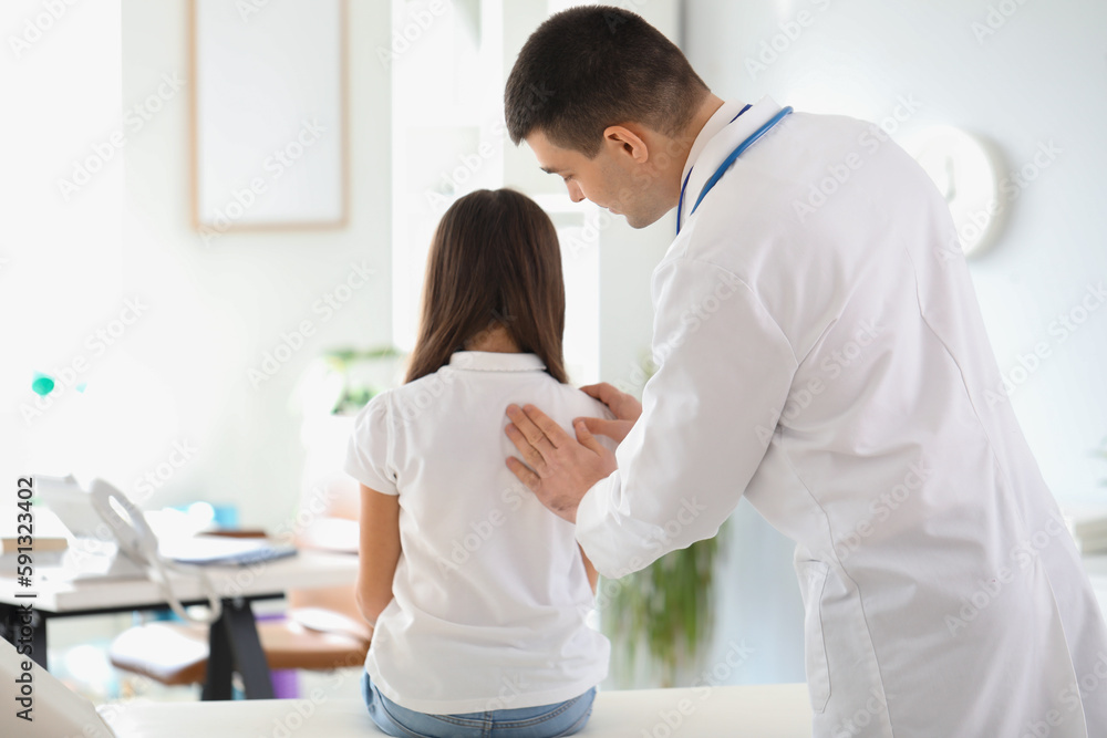 Obraz premium Doctor checking posture of little girl in clinic