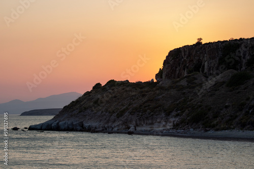 Sunset over the sea with rocks and mountains in the background. Sunset on the coast. Sunlight reflecting off the sea. 