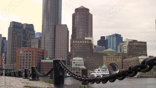 Boston skyline from Harborwalk Fan Pier Park in slow motion on a cool fall day by the water with chains in foreground  photo