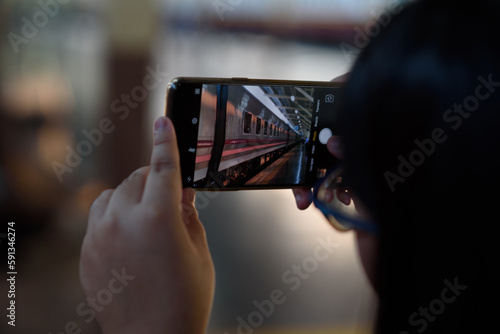 A person is photographing a train at Hua Lamphong station in Bangkok