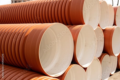 Orange plastic pipes used on a construction site. Orange PVC sewer pipe for outdoor use. Stacked in a row premium plastic pipes for wastewater