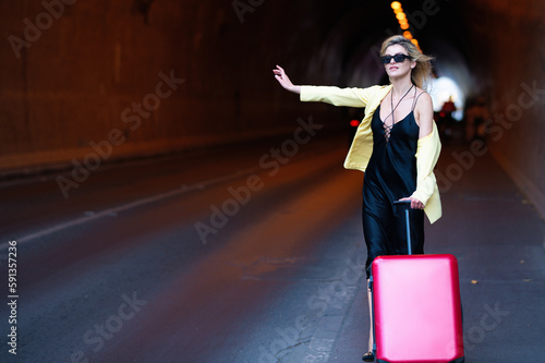 Dreams of travel. Woman with a suitcase take taxi. Woman tourist with travel bag. Businesswoman with travel suitcase on vacation. Business travel and adventure concept.