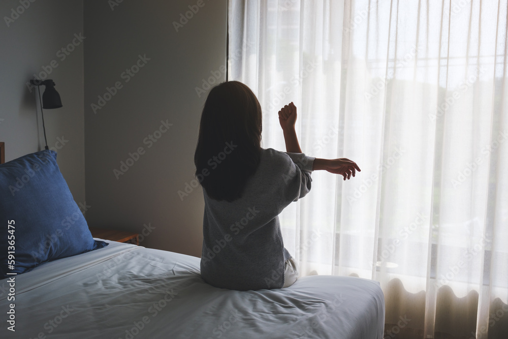 Rear view image of a woman do stretching after waking up in bedroom Rear view image of a woman do stretching after waking up in bedroom
