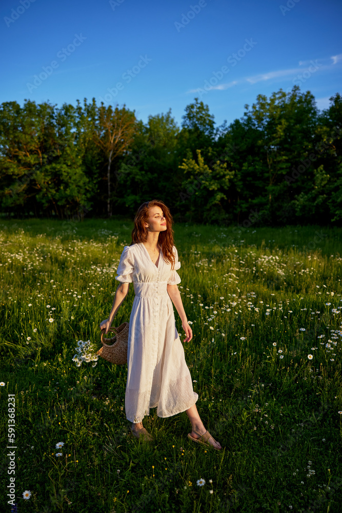 a beautiful woman in a light, light, summer dress is standing in a flowering meadow in the sunset light a beautiful woman in a light, light, summer dress is standing in a flowering meadow in the sunset light