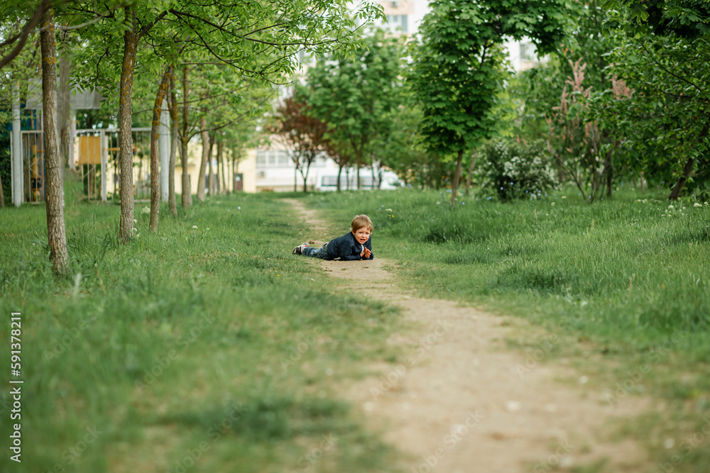 Inquisitive childhood. A little child boy outside looking far. A young boy walking on a sunny summer day. A cute boy is walking on the grass in a green summer park. Cheerful boy in a spring garden Inquisitive childhood. A little child boy outside looking far. A young boy walking on a sunny summer day. A cute boy is walking on the grass in a green summer park. Cheerful boy in a spring garden