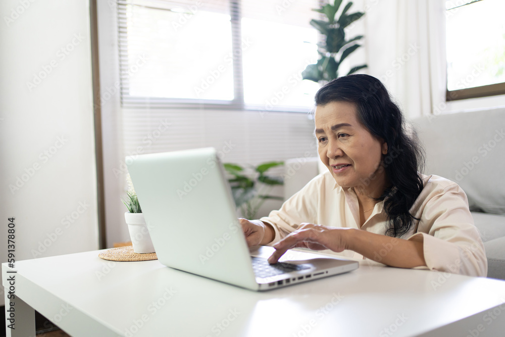 Middle age Asian woman Work from home. senior woman smiling Beautiful mature asian woman on laptop with technology concept Middle age Asian woman Work from home. senior woman smiling Beautiful mature asian woman on laptop with technology concept