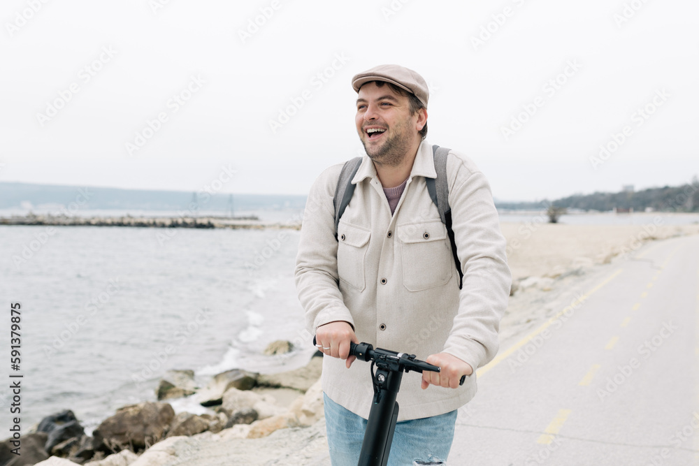 Obraz premium man in casual clothes moving on a scooter along the embankment