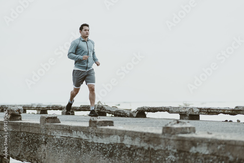 healthy lifestyle young fitness man running at seaside old bridge. Outdoor workout, Healthy lifestyle concept.