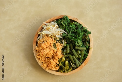 Urap or mix vegetables with grated coconut on wooden plate. Indonesian food on top view angle photo