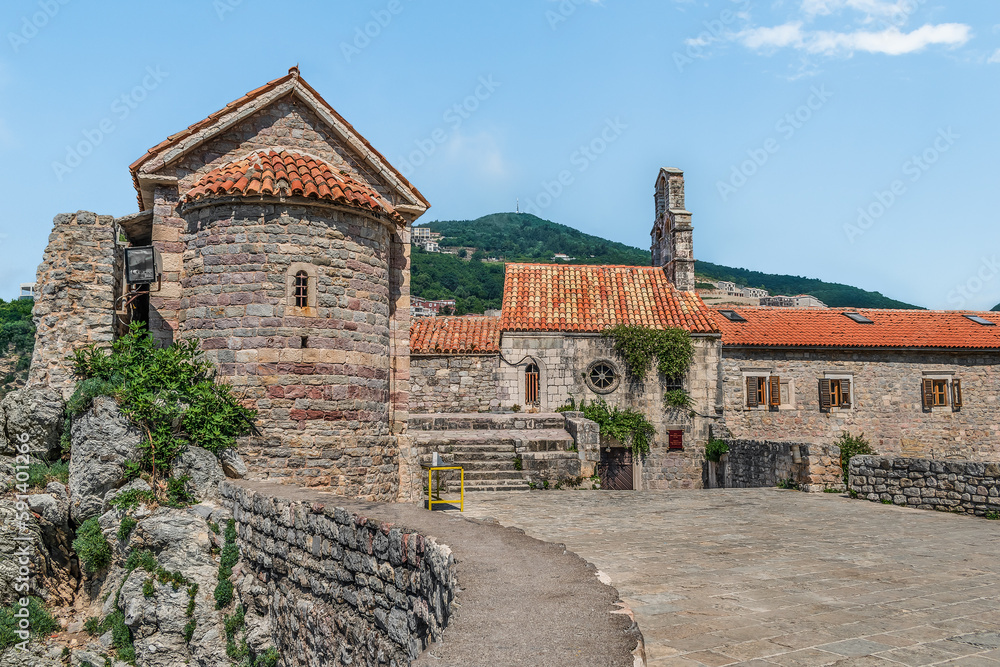 Observation deck and Catholic Church of Santa Maria in Punta in the Old Town of Budva, Montenegro. Historical urban landscape with old stone buildings with red tiled roofs in summer in the Balkans