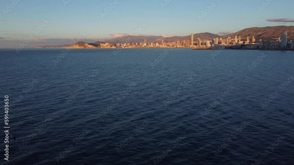 Aerial approach to the city of Benidorm early in the morning, with a seagull passing Aerial approach to the city of Benidorm early in the morning, with a seagull passing