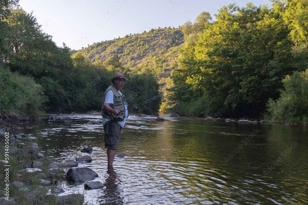Senior man fishing in the river in summer