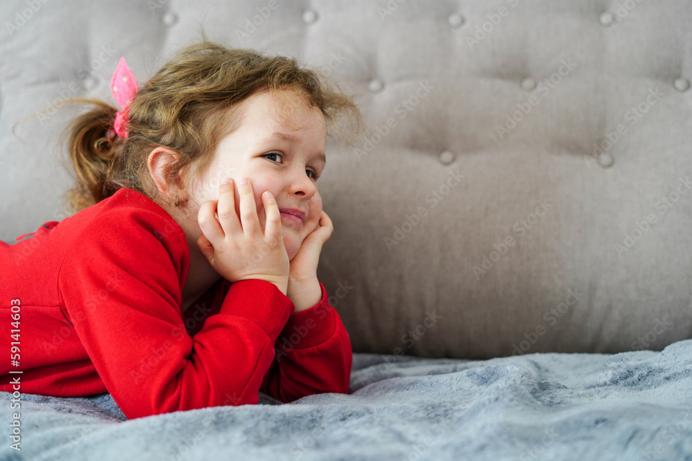 Funny little girl laying on the bed, happy childhood Funny little girl laying on the bed, happy childhood