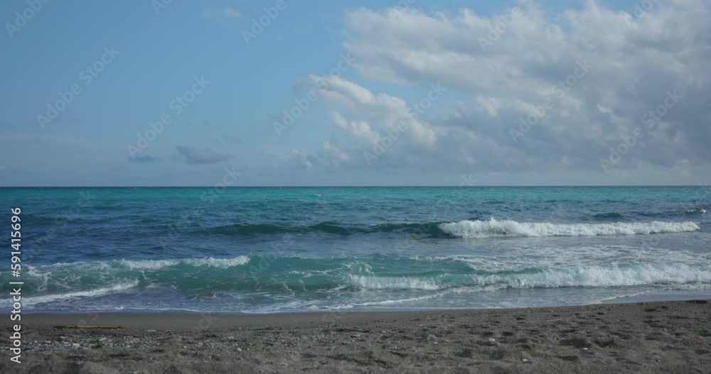 Static shot of waves crashing onto beach on a bright and cloudy day Static shot of waves crashing onto beach on a bright and cloudy day