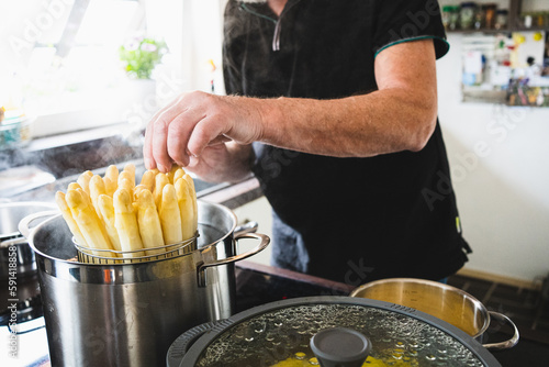 old man cooking asparagus in the kitchen