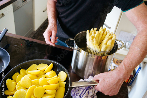 old man cooks asparagus and potato