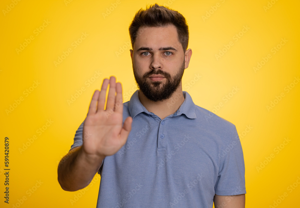 Angry man say No hold palm folded crossed hands in stop gesture, warning of finish, prohibited access, declining communication, body language, danger. Young guy on yellow background. People lifestyle Angry man say No hold palm folded crossed hands in stop gesture, warning of finish, prohibited access, declining communication, body language, danger. Young guy on yellow background. People lifestyle