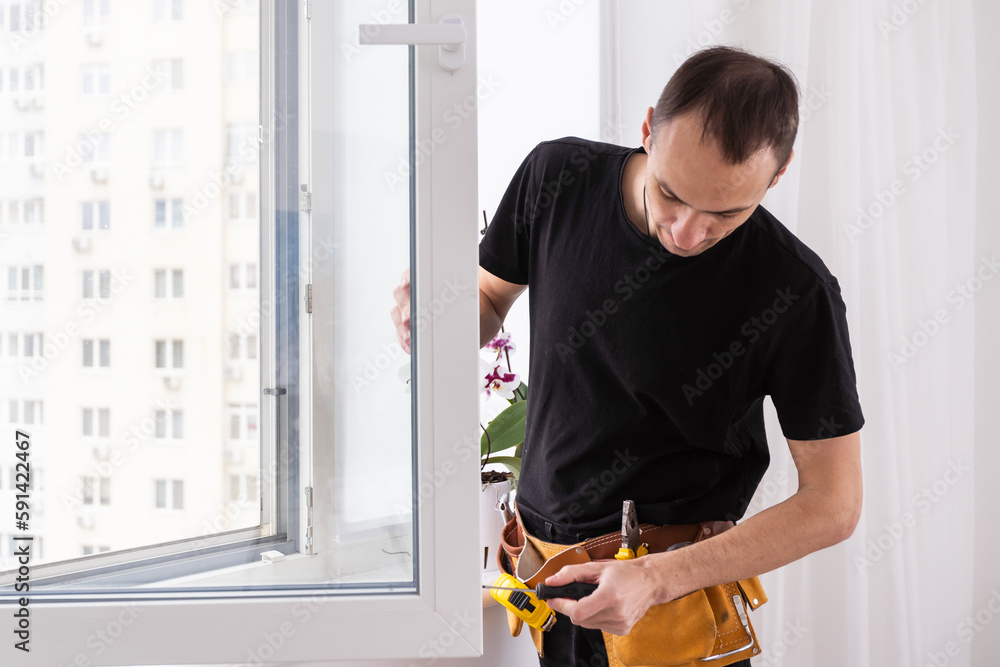 Worker adjusting installed window with screwdriver indoors, closeup Worker adjusting installed window with screwdriver indoors, closeup