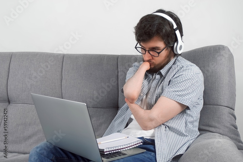 Disabled man student with amputated two stump hands studying on laptop at home and making notes in notebook. Problem of adaptation to life people with disabilities. Independent Invalid person.