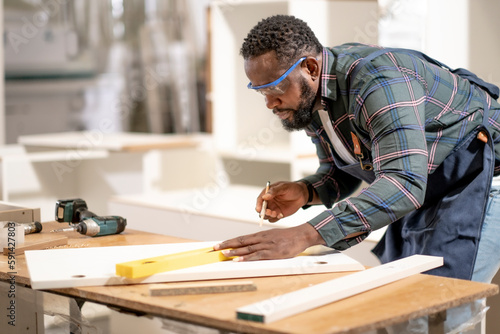 African American man does his work at furniture factory seriously and professtionally, carpenter ocupation, labor job holliday.