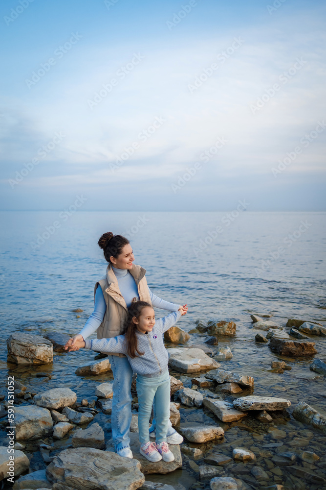 family weekend by the sea. happy mother and daughter have fun on a walk. sunset on the sea family weekend by the sea. happy mother and daughter have fun on a walk. sunset on the sea