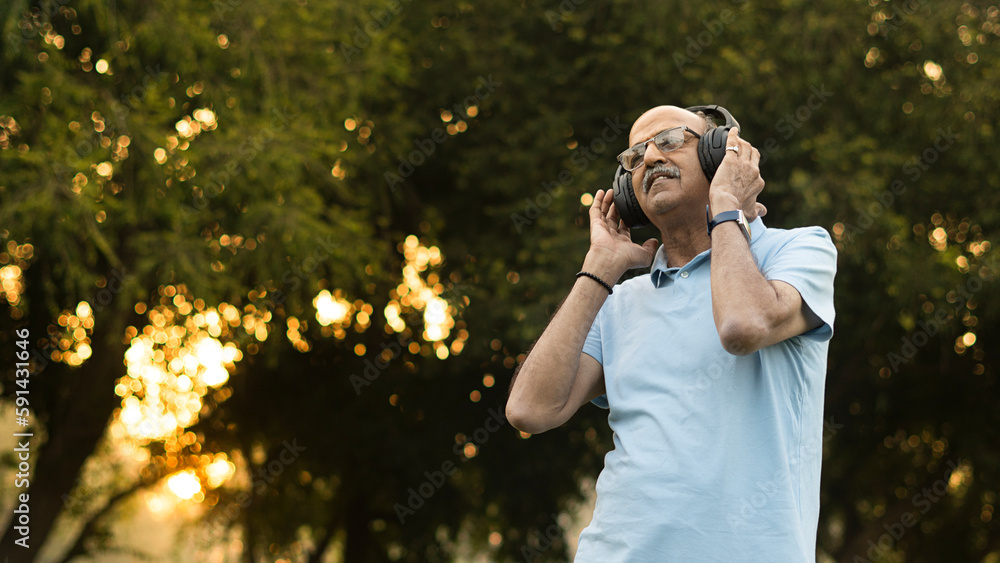 happy senior citizen male enjoying music in headphones in park happy senior citizen male enjoying music in headphones in park
