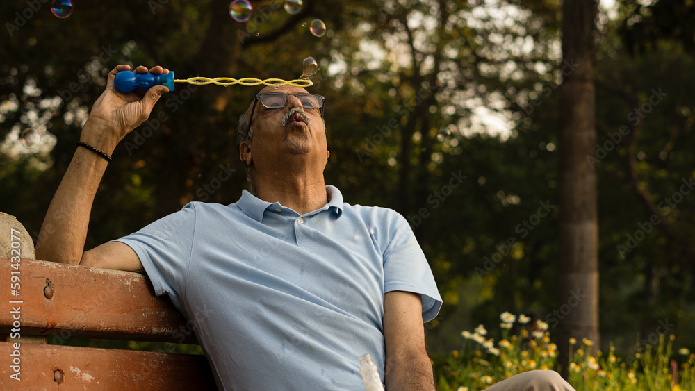 Fototapeta premium Senior citizen male in park playing with bubbles