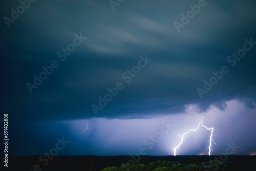 Long exposure of dramatic clouds in the sky and lightning illuminating the area