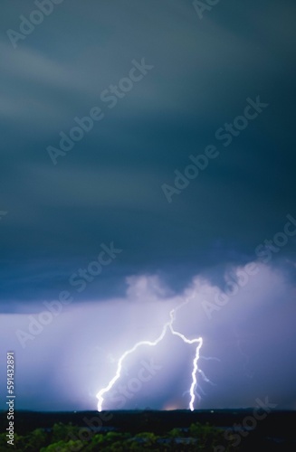 Long exposure vertical shot of dramatic clouds in the sky and lightning illuminating the area