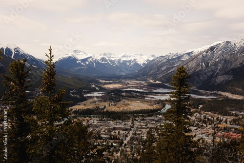 Aerial shot over the town Banff in Alberta Canada surrounded by snowy mountains © Rachelmcgrath/Wirestock Creators