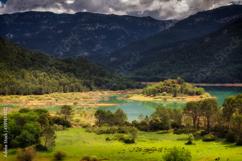 the meadow and the lake with sunlight illuminating the grass and mountains surrounding the lake